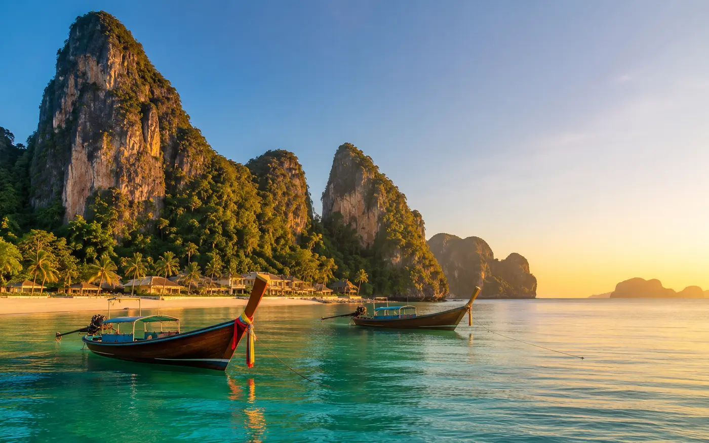 Longtail boats on a turquoise bay in Thailand at golden hour